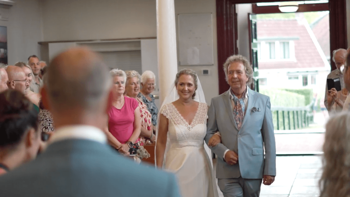 Bruid komt arm in arm binnen tijdens de ceremonie